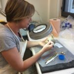 Isabelle Ducassou dégageant au scalpel les dépôts terreux des objets archéologiques.